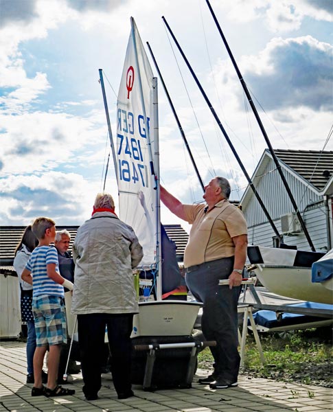 Blinde Menschen stehen vor einem Seegelboot