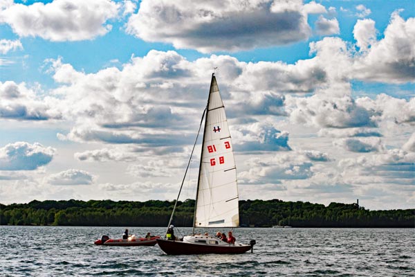 Kielboot mit leuchtendem weißem Großsegel auf den See