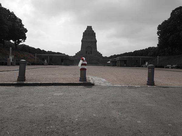 Blick auf das Völkerschlachtdenkmal Leipzig, von drei Pollern trägt einer eine rotweiße Mütze