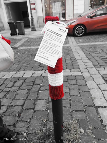 Straße in Zittau, ein grauer Poller trägt eine rotweißgestreifte Mütze