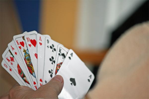 Ein Spieler hält in der linken Hand seine Skatkarten.