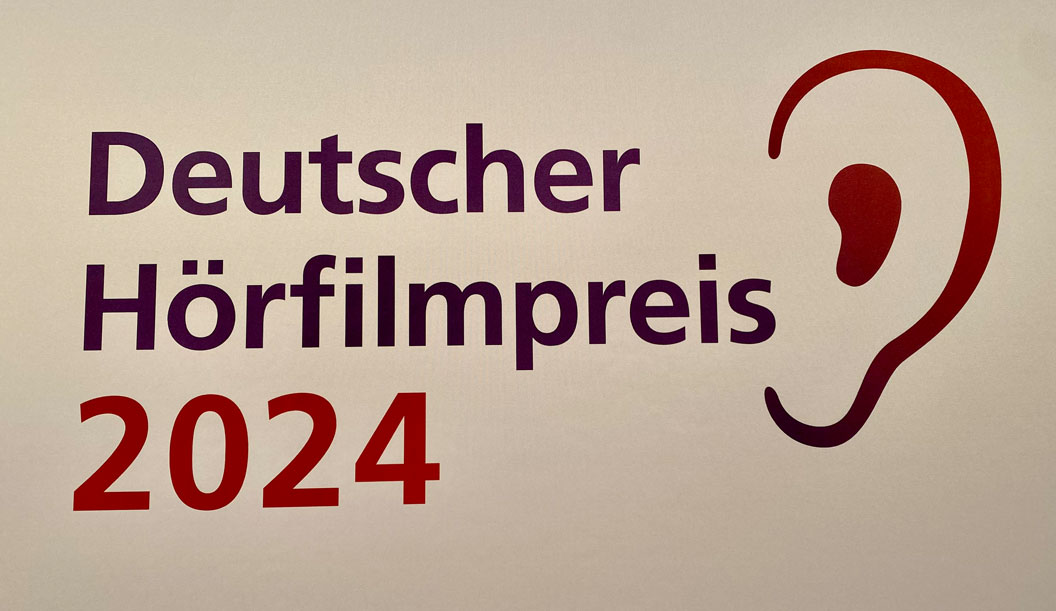 Schriftzug Deutscher Hörfilmpreis (lila) 2024 (rot) Rechts daneben ist ein grafisches Ohr mit dem Farbverlauf rot zu lila von oben nach unten abgebildet.