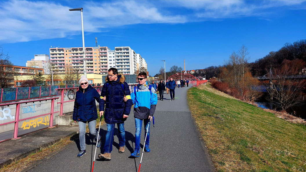 Zur ersten diesjährigen Langstockwanderung waren Raisa Beuthan, Andre Brendle und Dominik Schubert von der KO Zwickau (von links nach rechts) ganz vorn dabei. Rechts vom Weg fließt die Mulde. Links sind im Hintergrund Neubaublöcke zu sehen.