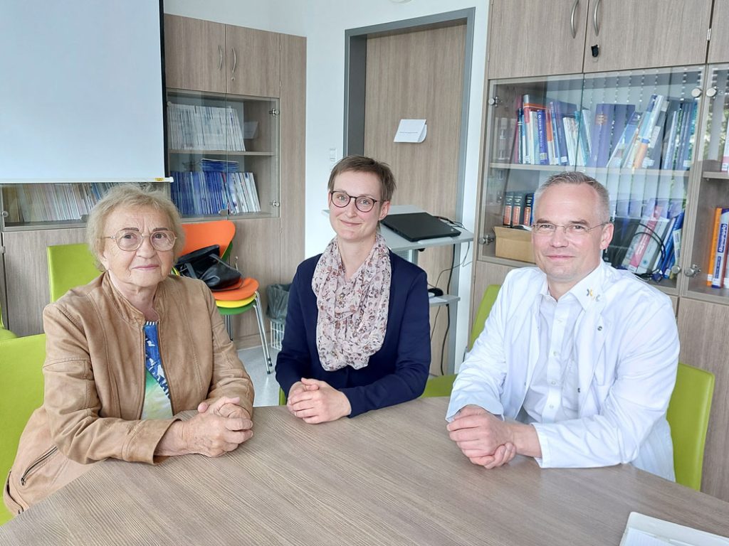 In einem Beratungsraum sitzen an einem Tisch von links nach rechts Frau Dr. Schmidt, Frau Smitkiewicz (BPA) und Chefarzt Hr. Dr. Breuer (Augenheilkunde, Städtischen Klinikum Dresden) und schauen in die Kamera.