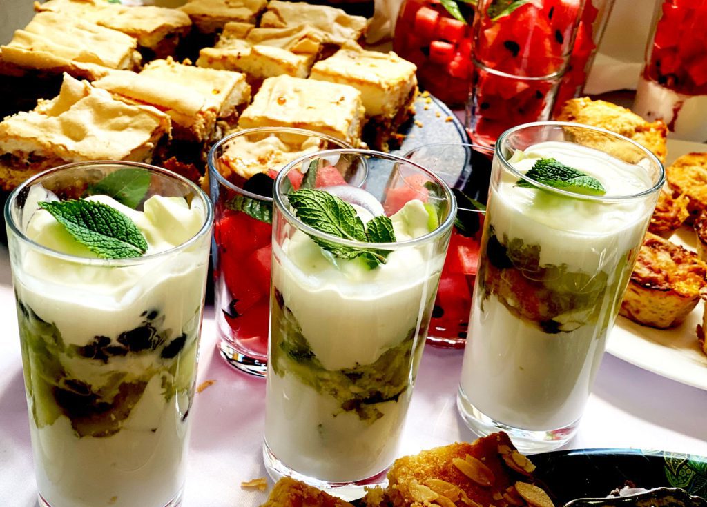 Ausschnitt aus dem Buffet mit Rhabarberkuchen, Gläsern mit Melone, Joghurt und Obstsalat befüllt.