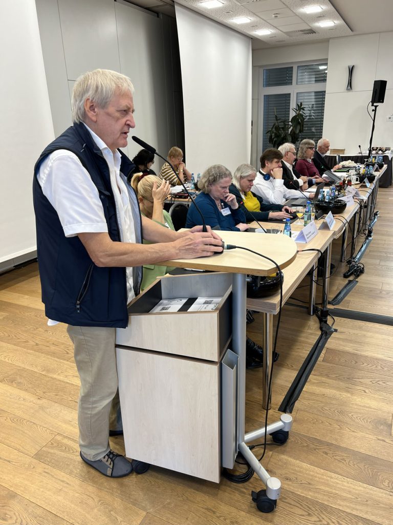 Herr Schneider hält eine Rede, welcher er auf dem VBR Freiburg Breisgau am 11. Oktober 2025 bei einem Beitrag links seitlich des Präsidium des DBSV hält. 